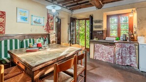 A rustic kitchen with wooden beams, a dining table, and a bench. - Villa Gabriella with Beautiful Garden (Piazzano)