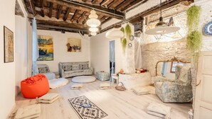 A cozy room with a stone wall, a blue sofa, a red bean bag, and a patterned rug. - Villa Gabriella with Beautiful Garden (Piazzano)