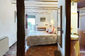 A bedroom with a bed, a bedside table, a lamp, and a view of the outside.