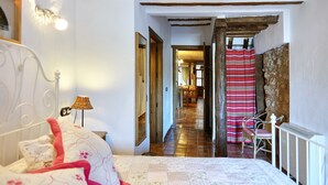 A bedroom with a bed, a nightstand, a lamp, a chair, and a view of a hallway leading to another room. - Room 'Tranco' with Mountain View and Private Terrace (Hornos)