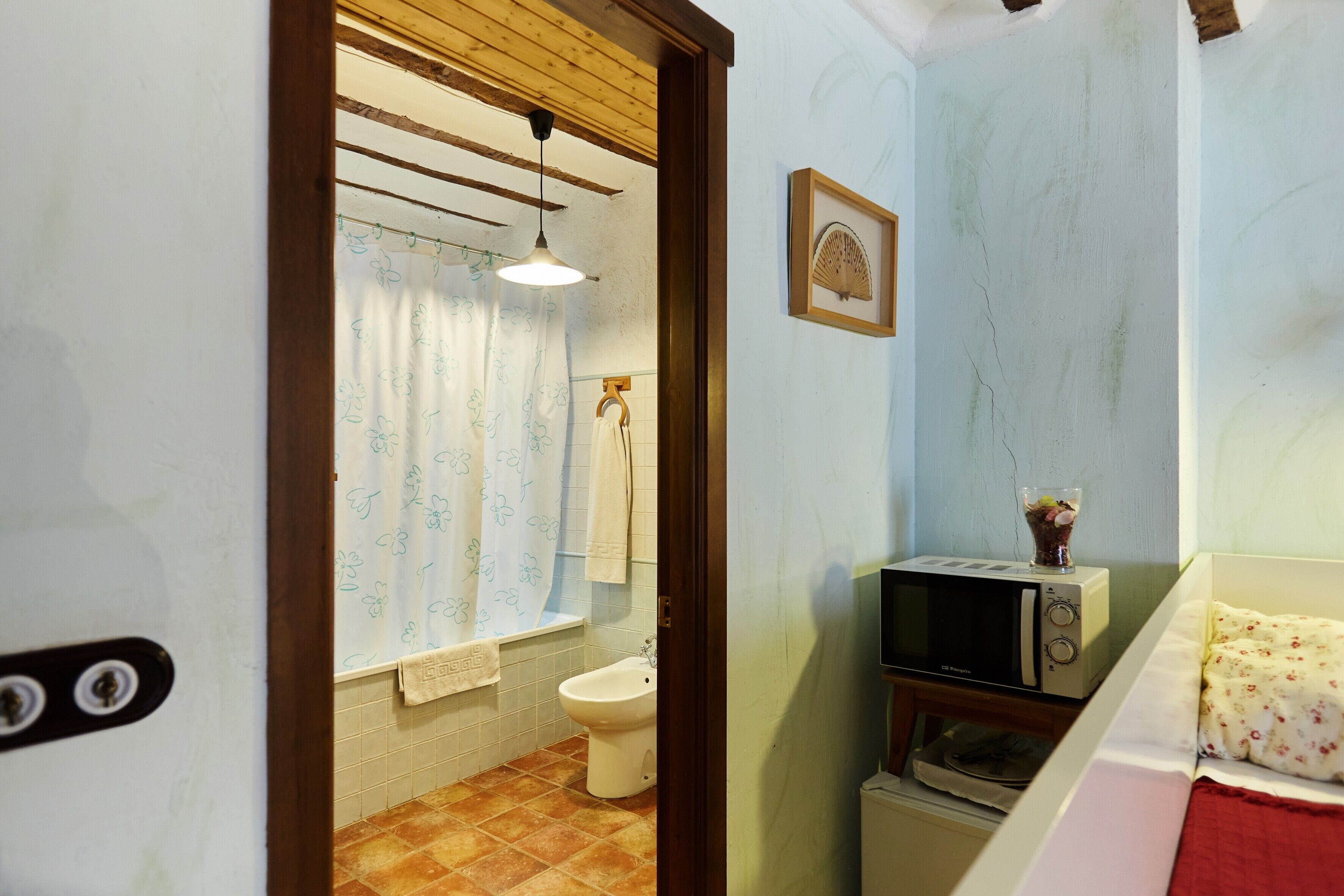Une salle de bain équipée de toilettes, d’un bidet et d’un four à micro-ondes posé sur une petite table.