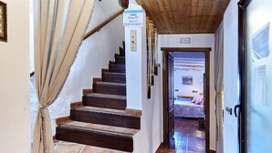 Una escalera que conduce a un dormitorio con cama, un cartel en la pared y una puerta a la derecha.