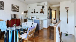 Un espacio habitable compacto con kitchenette, un comedor con mesa y sillas, y una zona de estar con sofá.