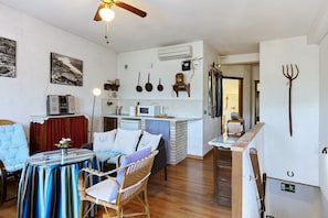 A compact living space with a kitchenette, a dining area with a table and chairs, and a seating area with a sofa.