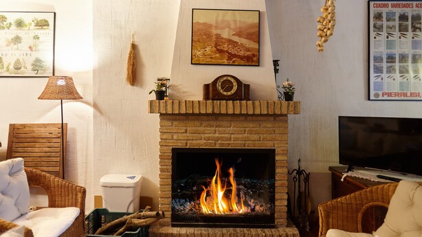 Una sala de estar con chimenea, muebles de mimbre, un televisor y obras de arte en las paredes.