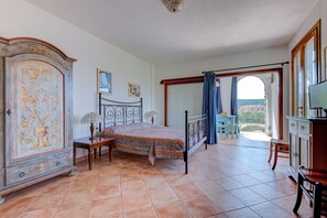 Une chambre à coucher avec un lit, une armoire, un bureau et une vue sur l’extérieur, visible à travers une porte.