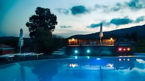 A pool area with a building in the background, a tree, and a mountain range. - Apartment 'Trilocale Bonalaccia 2' with Shared Pool, Private Terrace and Wi-Fi (Campo nell'Elba)