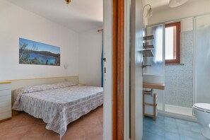 Ein Schlafzimmer mit Bett, ein Badezimmer mit Dusche und ein Fenster.