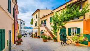 A narrow cobblestone street lined with colorful buildings, a bicycle, and potted plants. - Apartment 'Trilocale Bonalaccia 2' with Shared Pool, Private Terrace and Wi-Fi (Campo nell'Elba)