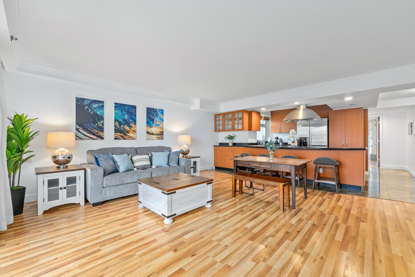 A modern living room with a grey sofa, wooden coffee table, and a dining area with a wooden table and chairs.