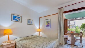 Una camera da letto con un letto, due lampade da comodino, un tavolino con una sedia e un balcone con tavolo e sedie.