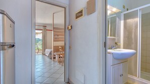Een badkamer met wastafel, spiegel en douche.
