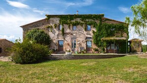 A stone building with ivy, a front door, and a small porch with potted plants. - Apartment 'Porcilaia' with Shared Pool, Private Terrace and Shared Garden (Sorano)