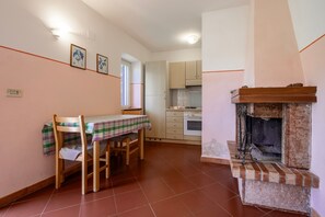 A kitchen with a fireplace, a dining table with chairs, and a window with blinds. - Apartment 'Porcilaia' with Shared Pool, Private Terrace and Shared Garden (Sorano)