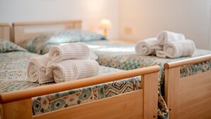 A hotel room with two wooden beds, each with a patterned bedspread and pillows. There are rolled towels on the beds. - Room 'Camera Sud' with Shared Pool, Shared Terrace and Wi-Fi (Sorano)