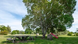A picnic area with a table and benches, surrounded by trees and a playground slide. - Room 'Camera Sud' with Shared Pool, Shared Terrace and Wi-Fi (Sorano)