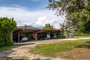 A covered parking area with cars and a blue tractor.