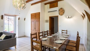 Un comedor con una mesa de madera dispuesta para seis personas, rodeada de sillas de madera, un sofá y una araña.