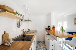 A compact kitchen with a wooden countertop, built-in appliances, and a small dining area.