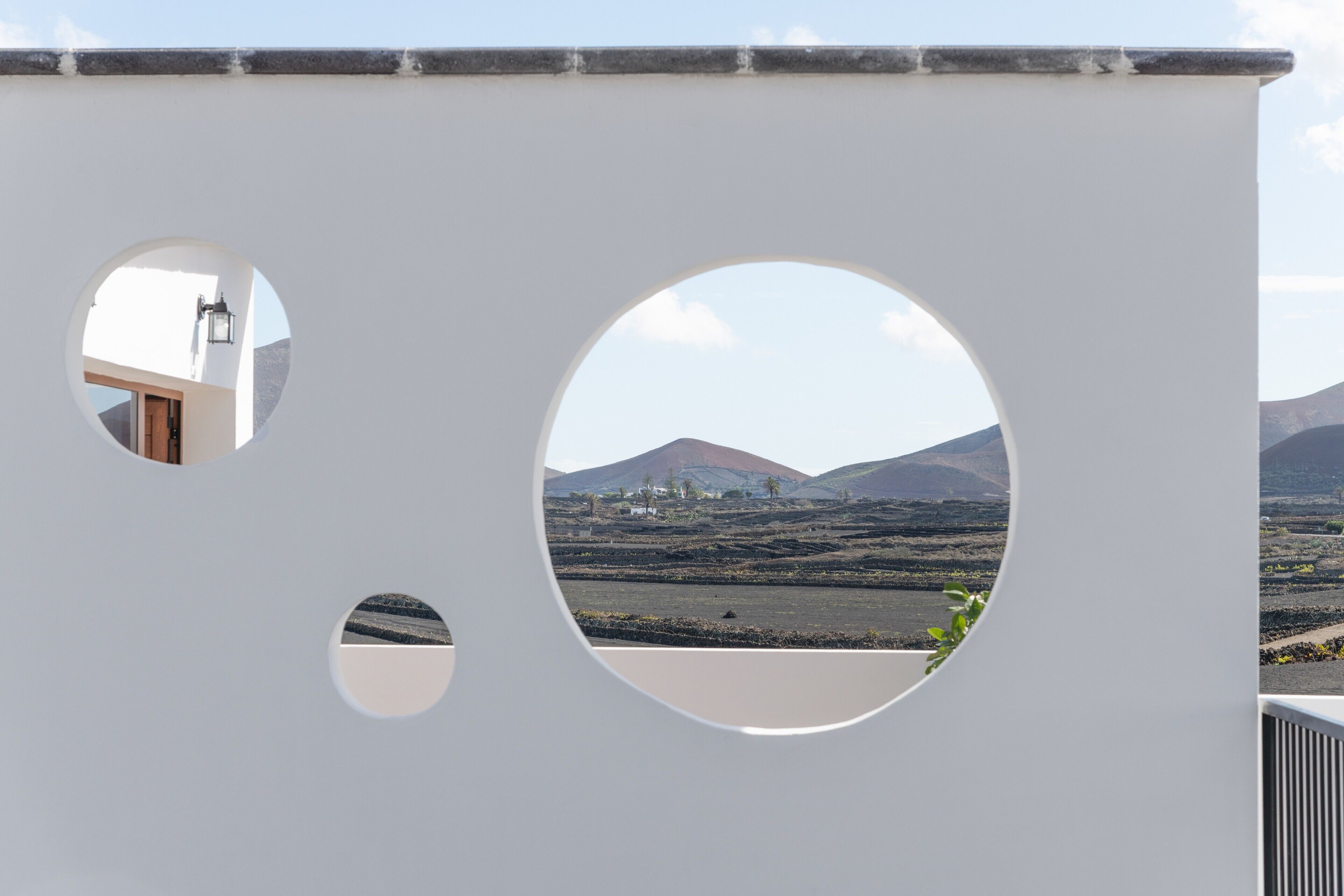 A modern building with circular cutouts revealing a mountainous landscape.