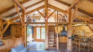 Una cabaña rústica de madera con un dormitorio en el altiloce, una cocina y un comedor.