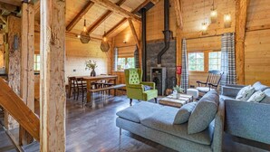 L’intérieur d’un chalet en bois comprend un coin repas, une cheminée et un canapé.