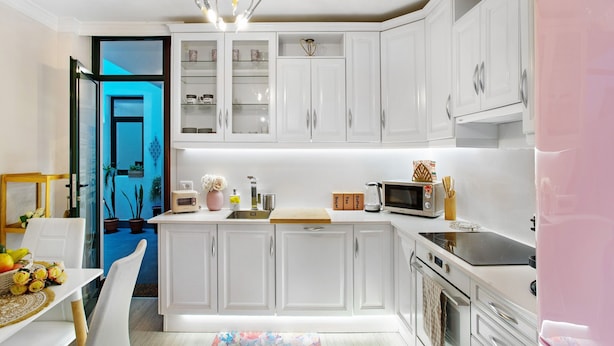 A modern kitchen with white cabinets, a microwave, a toaster, and a sink.