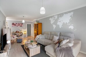Moderni olohuone, jossa on sohva, sohvapöytä ja televisio.