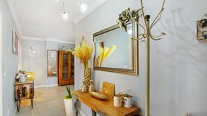 A hallway with a wooden console table, a mirror, and a coat rack.