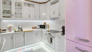 A modern kitchen with white cabinets, a pink refrigerator, a microwave, and a coffee maker.
