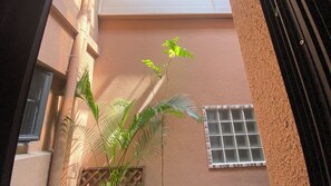 A narrow alleyway with a building featuring a textured wall and a window with a grid pattern. - Hôtel de Flore (Tainan)