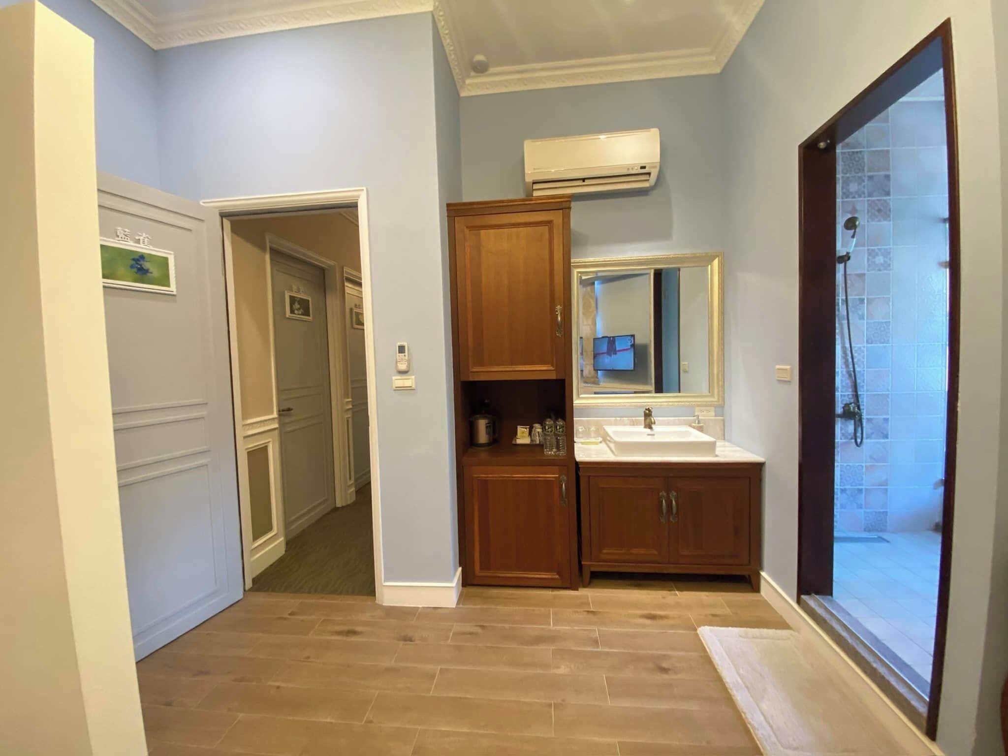 A bathroom with a wooden vanity, a sink, a mirror, and a shower area.