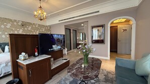 A hotel room with a TV, wooden cabinet, marble table, and a floral arrangement. - Hôtel de Flore (Tainan)