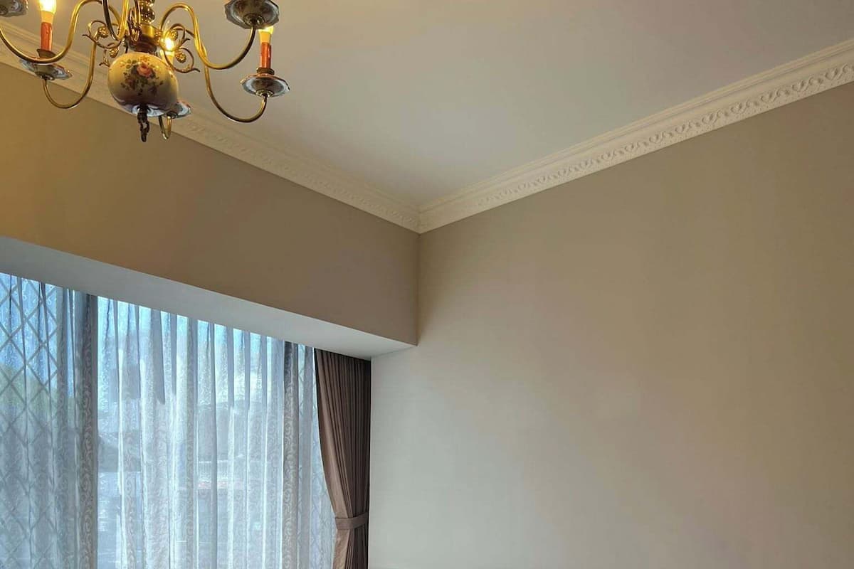 A hotel room with a large bed, a round table, and a window with sheer curtains.