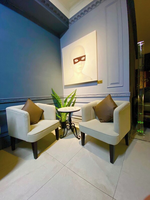 A room with two white armchairs, a small round table, and a potted plant. - Hôtel de Flore (Tainan)