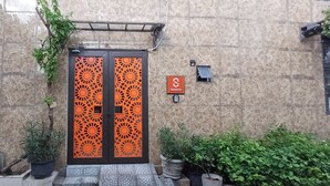 Entrada de un edificio con una puerta naranja decorativa, un letrero que dice "Seashine" y plantas en macetas alrededor de la entrada.