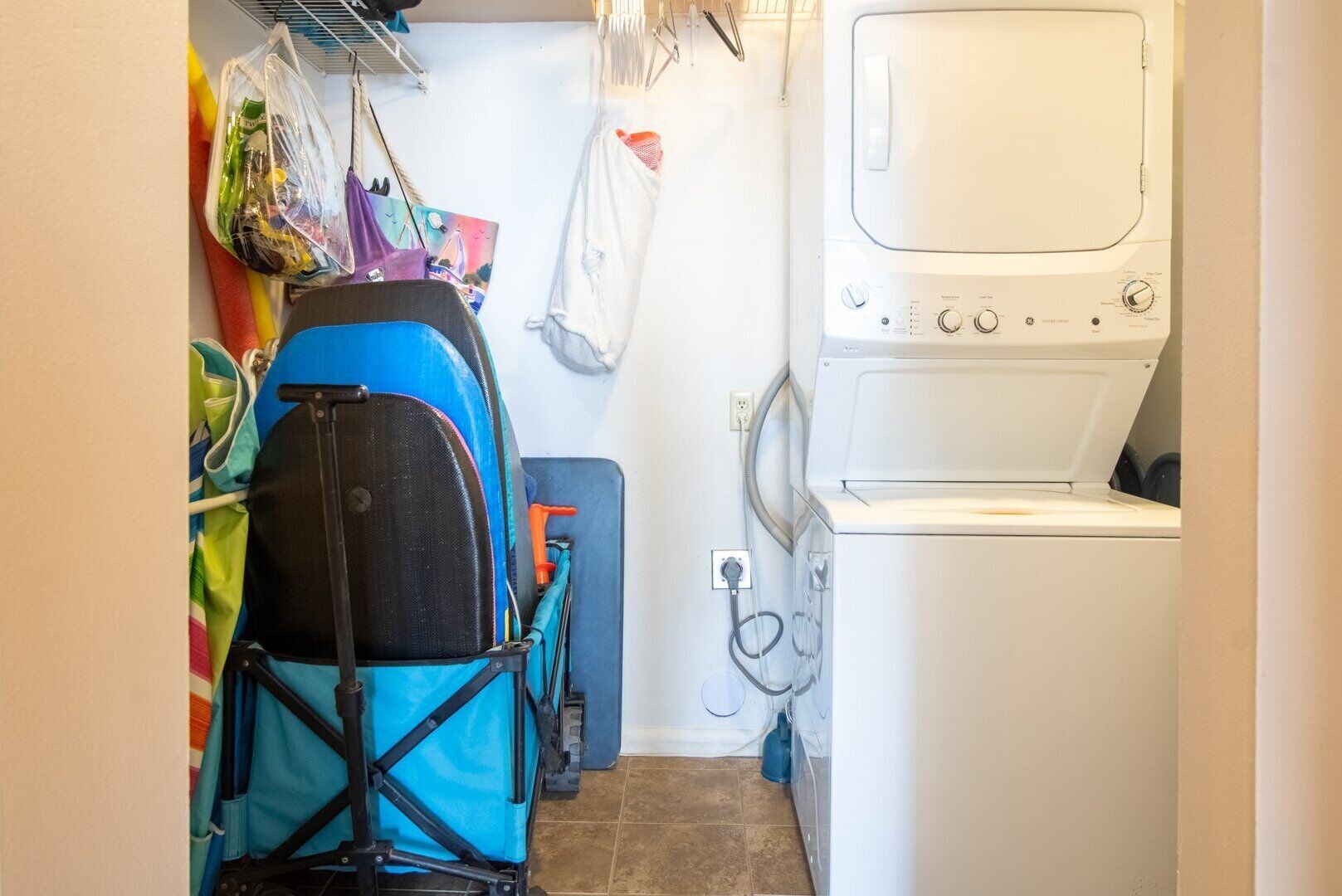 A laundry room with a washing machine, a drying machine, and a blue folding chair.
