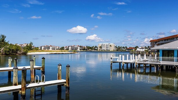 A waterfront property with a dock, calm water, and buildings in the background.