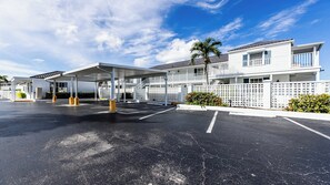 A motel with a covered parking area, a fenced walkway, and a two-story building with a balcony.