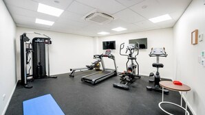 A gym with cardio machines, weightlifting equipment, and a blue mat.
