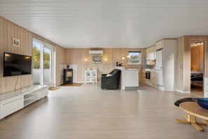 A modern interior with a TV, seating area, kitchen, and a fireplace.