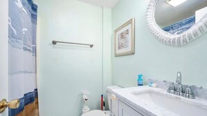 A bathroom with a toilet, sink, and a towel rack. - Charming 1-bedroom condo in tranquil Dennis with AC (Dennis)