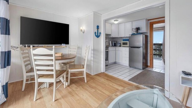 A compact living space with a dining area, kitchenette, and a view to the outside. - Charming 1-bedroom condo in tranquil Dennis with AC (Dennis)
