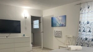 A bedroom with a bed, a TV, a dresser, and a painting on the wall.
