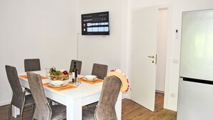 A modern dining area with a white table, grey chairs, and a flat-screen TV mounted on the wall. - La Conca by Interhome (Formia)