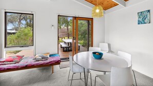 Un interno moderno con zona pranzo, una panca con cuscini e vista su un patio esterno attraverso una porta vetrata.