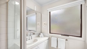 A bathroom with a white sink, mirror, and window. - Fairhaven Escape (Fairhaven)