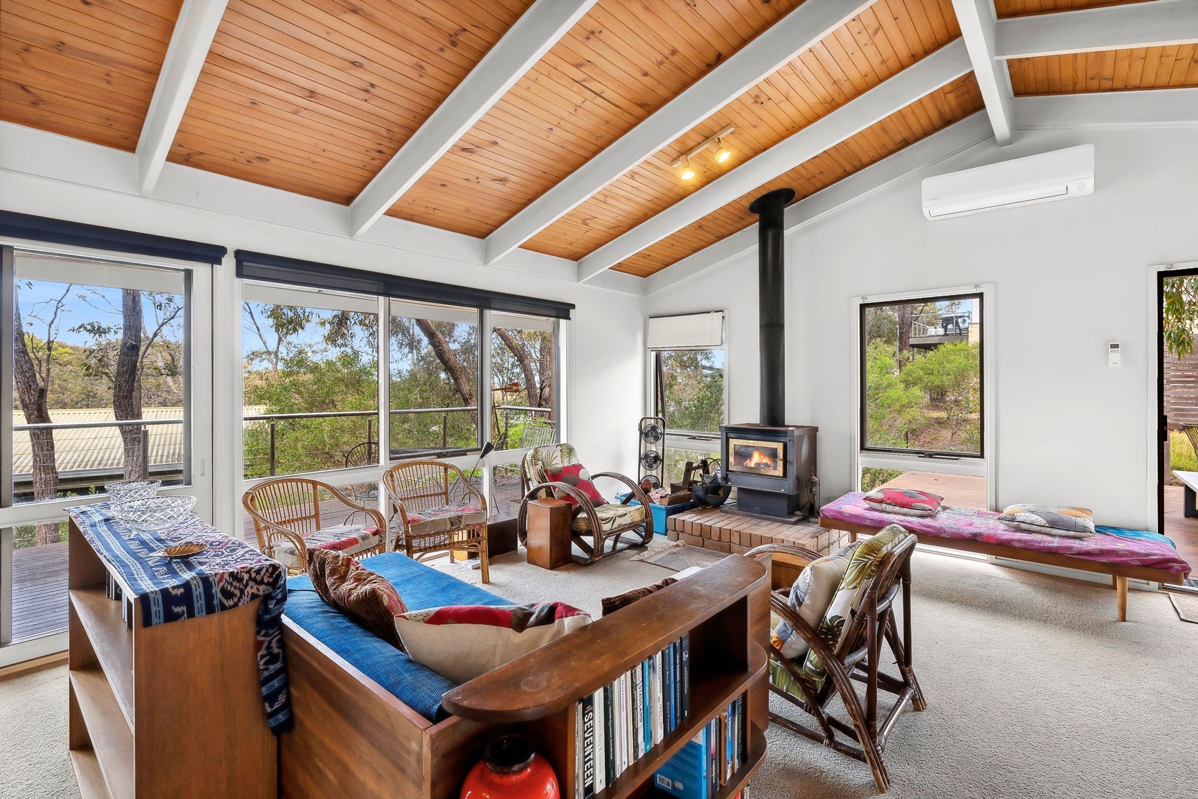 A spacious living area with a high ceiling, large windows, a fireplace, and a variety of seating options.