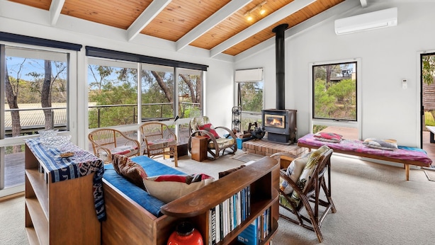 A spacious living area with a high ceiling, large windows, a fireplace, and a variety of seating options. - Fairhaven Escape (Fairhaven)