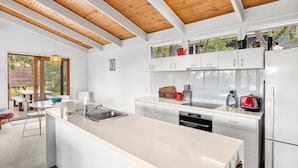 A modern kitchen with white cabinetry, a large island, and a wooden ceiling. - Fairhaven Escape (Fairhaven)